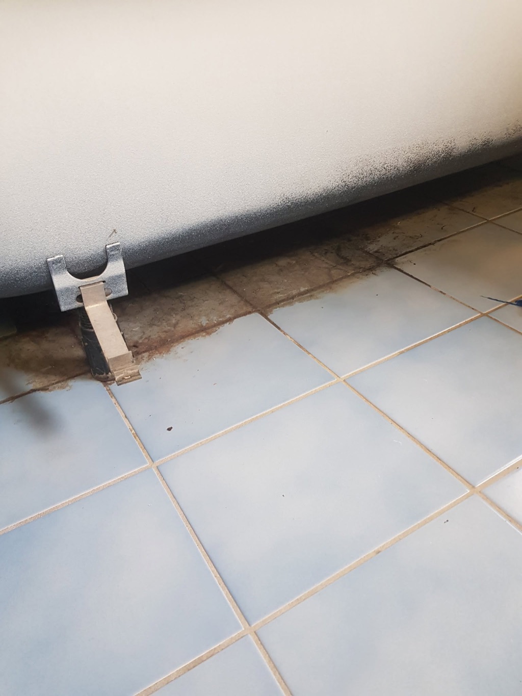 Et område under en frittstående hvitevare før rengjøring.