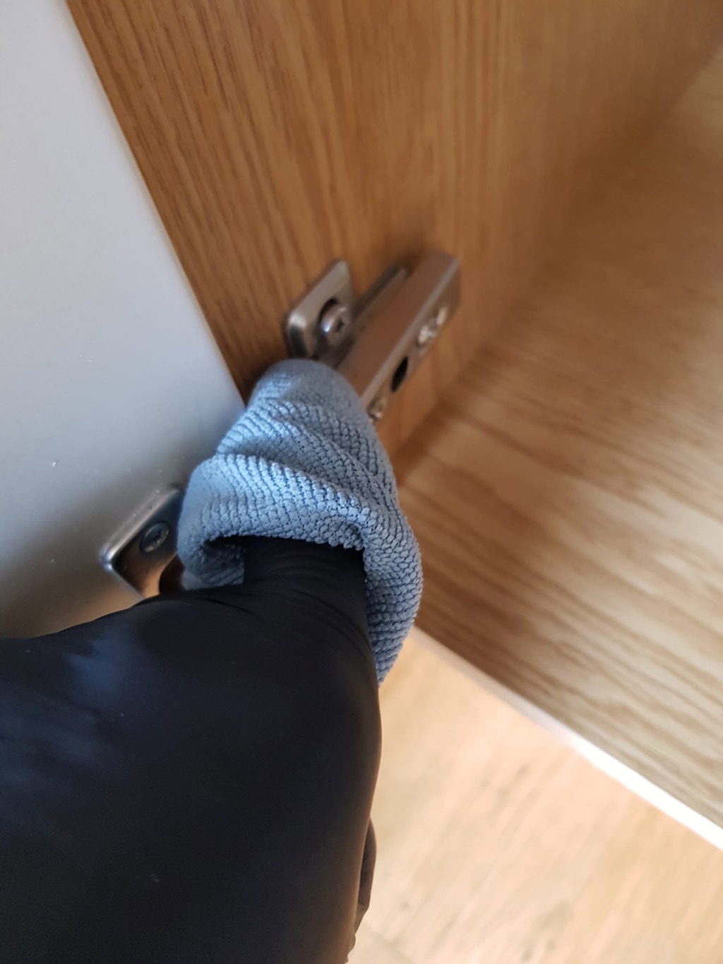 En skapdørhengsel rengjøres med klut.