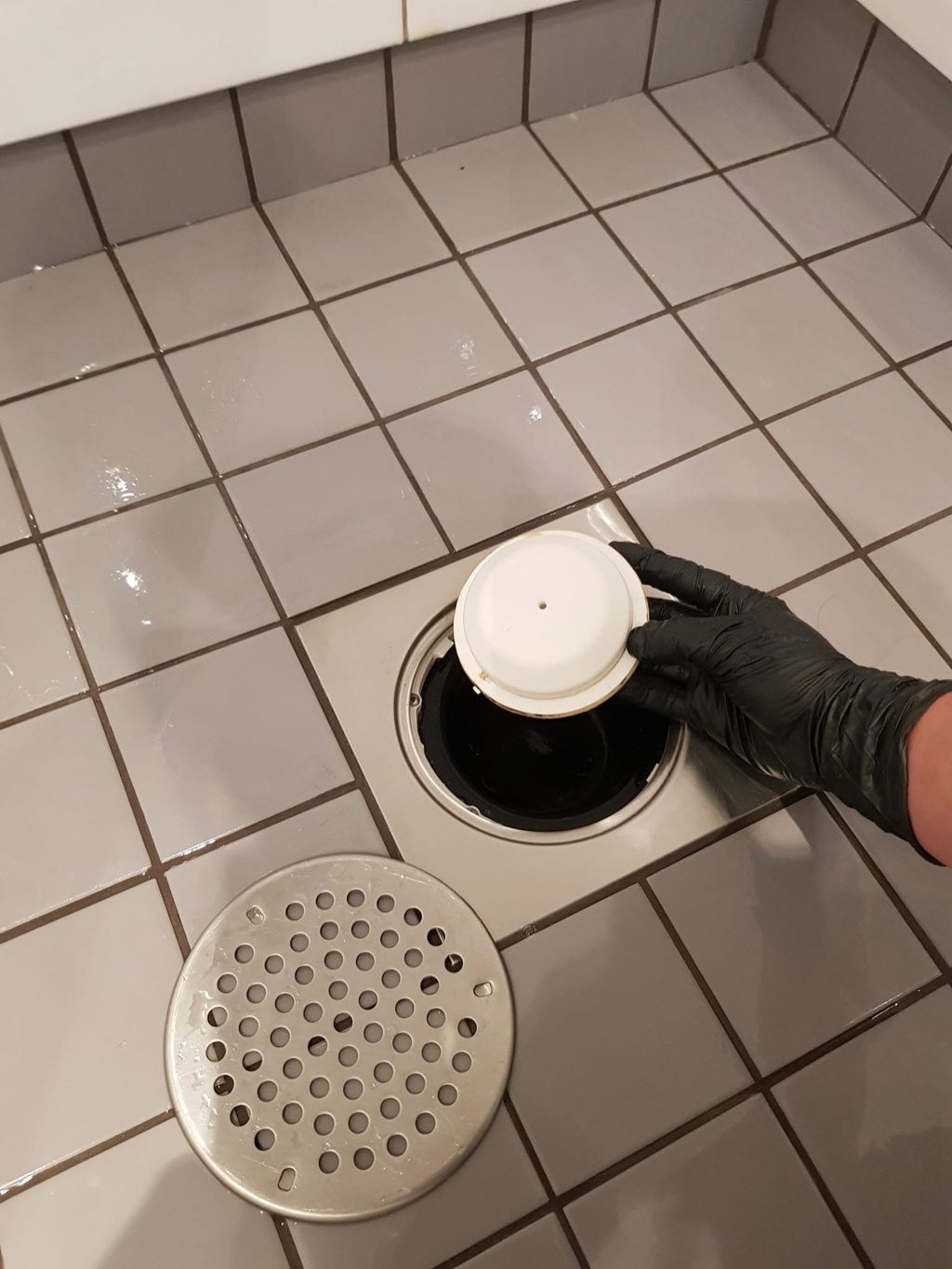 Margaret holder en del fra et åpent sluk under rengjøring av badet i Moss.